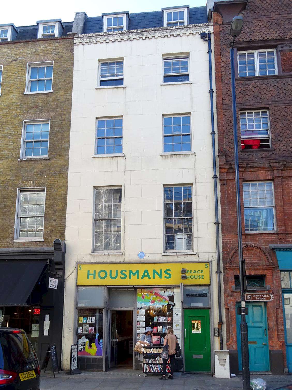The front of Housmans bookshop, a tall, narrow building with a yellow and green sign.