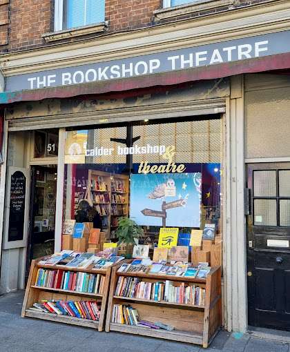 Front view of The Calder Bookshop, with books displayed outside on wooden shelves and a sign above the entrance.