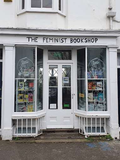 The front of The Feminist Bookshop in Brighton, featuring large windows filled with books and posters, and a welcoming entrance. The shop's name is displayed above the door. © Anna Paulins