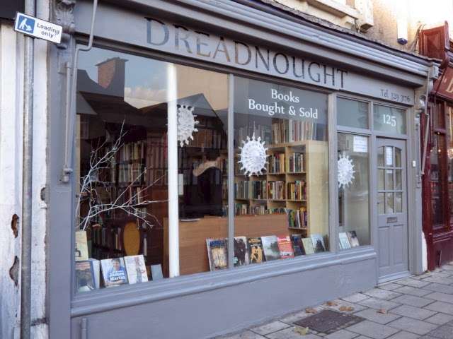 The front of Dreadnought Books in Bristol, featuring large windows displaying an inviting interior filled with books. The shop's signage reads "Dreadnought Books" with "Books Bought & Sold" written below. © Dreadnought Books