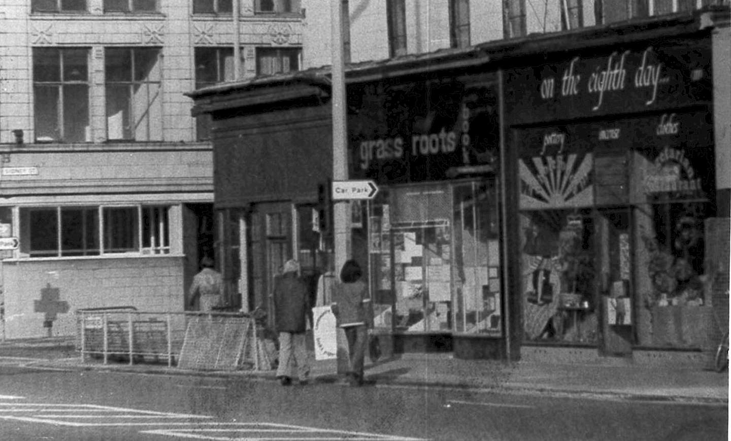 Black and white photo of Grass Roots Bookshop in Manchester with its distinctive black shopfront.