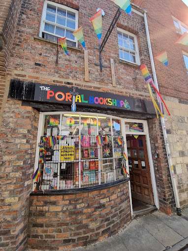 The exterior of The Portal Bookshop, decorated with colourful pride flags and a sign above the window.